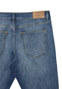 Jeans in denim blu con vita alta, due tasche posteriori, cuciture dorate e un'etichetta in pelle beige sulla vita.