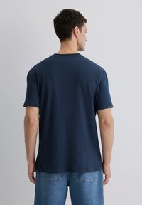 Marineblaue Baumwoll-T-Shirt mit kurzen Ärmeln und Rundhalsausschnitt, mit einer lässigen Passform und glatter Textur. Sichtbares Steppdetail am Saum.