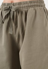 Khaki joggers met elastische tailleband en trekband, uitgevoerd in zachte stof, met een relaxte pasvorm en zijzakken voor comfort en functionaliteit.
