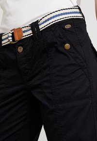 Zwarte cargoshorts met een gestructureerde afwerking, voorzien van een gestreepte geweven riem in marineblauw en wit, en metalen hardware-accenten op de zakken.
