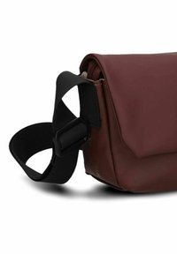 Borsa impermeabile marrone di forma arrotondata, dotata di una tracolla nera regolabile, chiusura a zip e texture opaca liscia.