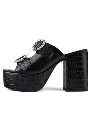 Sandales à plateforme noires avec un motif en crocodile texturé, dotées de deux grandes boucles ornées de strass sur le dessus.