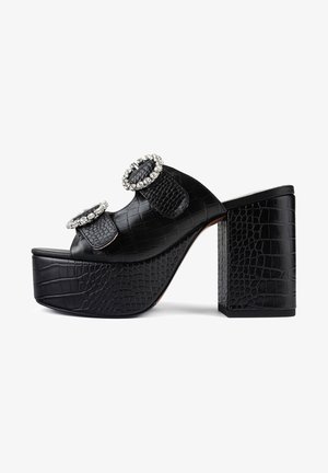 Czarne sandały na platformie z fakturą przypominającą skórę krokodyla, z dwoma dużymi klamrami ozdobionymi cyrkoniami na górnej części.