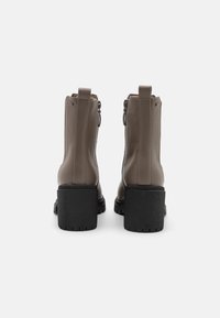 Bottes noires en cuir avec une finition texturée, dotées d'un talon en caoutchouc noir épais et d'une fermeture éclair à l'arrière.