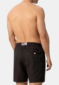Pantaloni da bagno neri con un motivo a stampa totale, vita elasticizzata con etichetta del logo e tasca laterale. Tessuto morbido.