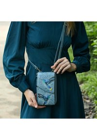 Lichtblauwe crossbody tas met reliëf vogelontwerp, gouden hardware en een gestructureerde afwerking. Beschikt over een schouderband en meerdere compartimenten.