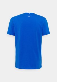 Camiseta de algodón azul con mangas cortas y cuello redondo. Presenta un pequeño logo en la parte posterior, textura suave y ajuste estándar.