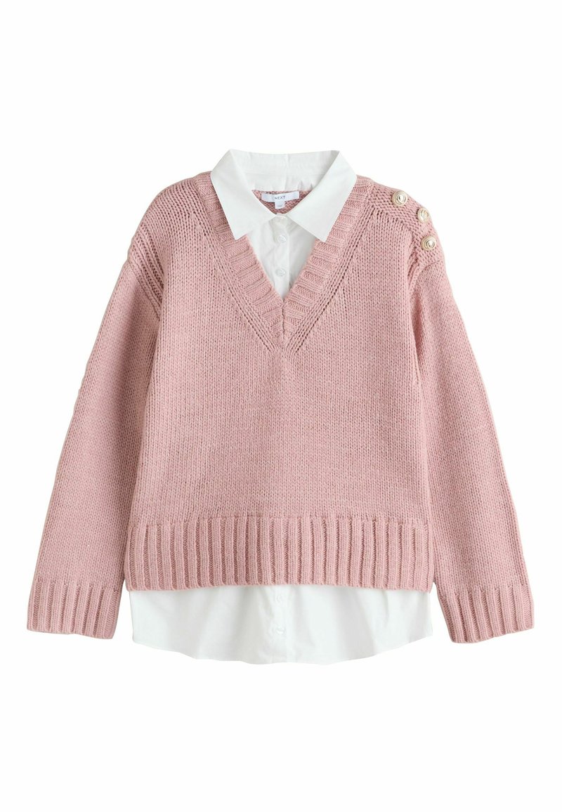 Pull rose tricoté avec col en V, ourlet côtelé et boutons décoratifs sur l'épaule, porté sur une chemise blanche à col.