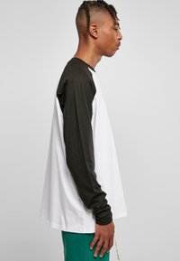 Langarm-T-Shirt mit weißem Körper und schwarzen Ärmeln, aus Baumwolle, mit lockerer Passform und Rundhalsausschnitt.