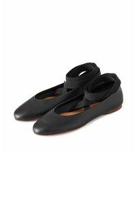 Bailarinas de cuero negro con punta afilada y correas elásticas cruzadas para un ajuste seguro. Suela plana con una textura suave y un detalle minimalista.