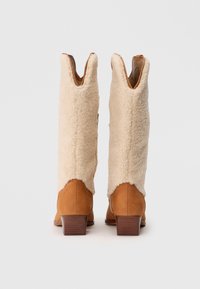 Stivali al ginocchio in pelle color cuoio e pelliccia sintetica crema con un'apertura a forma di V nella parte superiore e un modesty blocco del tacco. Tessuto texturizzato e accenti in pelle liscia.