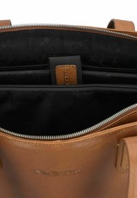 Borsa tote in pelle marrone con chiusura a zip e fodera in tessuto nero. Presenta più scomparti, tra cui un divisorio imbottito e un dettaglio con logo.