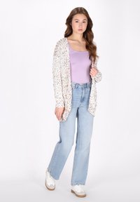 Cardigan de tricot ușor, multicolor, peste un top de lavandă, asortat cu blugi cu talie înaltă și adidași albi, având o croială lejeră.