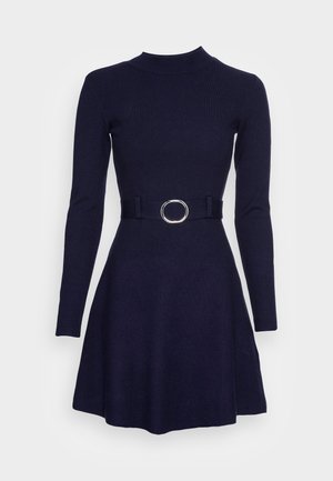 Vestido de canalé en color navy con mangas largas, escote simulado y cintura ajustada. Presenta un cinturón de tela con un acento de hebilla redonda plateada.