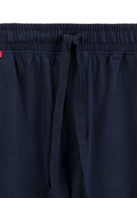 Granatowy pas elastyczny z regulowanym sznurkiem. Miękka bawełna o gładkiej teksturze. Posiada małą czerwoną metkę z logo po lewej stronie.