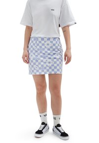 Mini-jupe à carreaux bleu clair avec motifs floraux, associée à un t-shirt blanc et des baskets noires, mettant en valeur un style décontracté.