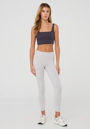 Leggings grigie e un top a canotta corto grigio scuro. I materiali sono lisci, con un design aderente e senza motivi visibili o dettagli in metallo.