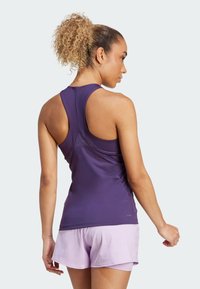 Lilla atletisk tanktop med racerback-design, lavet af glat, strækbart stof. Sammen med lyse lavendelfarvede shorts, der fokuserer på funktionalitet.
