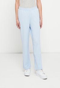 Ανοιχτό μπλε φόρμες από μαλακό ύφασμα, με ελαστική μέση και ίσια πόδια. Συνδυασμένο με λευκά αθλητικά παπούτσια.