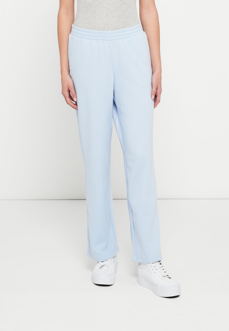 Ανοιχτό μπλε φόρμες από μαλακό ύφασμα, με ελαστική μέση και ίσια πόδια. Συνδυασμένο με λευκά αθλητικά παπούτσια.