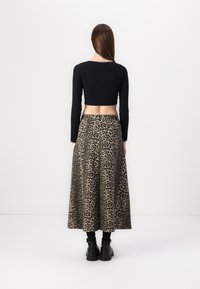 Pulover negru scurt cu mâneci lungi, combinat cu o fustă lungă, fluida, cu imprimeu leopard. Ţinuta are un bust ajustat și un tiv larg.