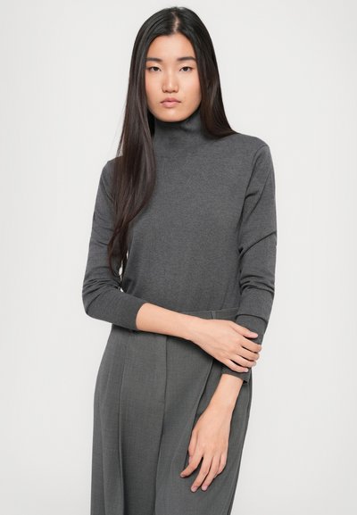 Pull à col roulé gris à manches longues ; texture douce et tricotée. Associé à un pantalon gris ajusté, mettant en valeur un design élégant et épuré.