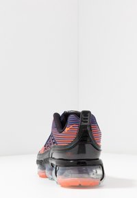 Svart löparsko med en strukturerad ovandel och blå och orange ränder, genomskinlig sula samt orangea accenter på hälen och logotypen.