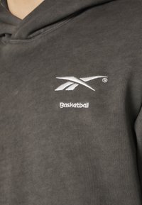 Felpa grigia in tessuto morbido con logo ricamato bianco e la parola "Basketball" sul davanti. Design semplice e dalla vestibilità rilassata.