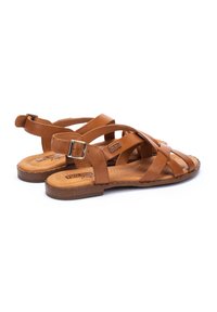 Sandales en cuir marron avec des sangles croisées, boucle réglable, semelle plate et semelle intérieure rembourrée. Dotées de détails de couture et du logo de la marque.