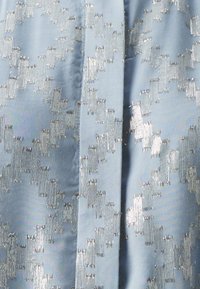 Lichtblauwe stof met een glinsterend zilveren geometrisch patroon, met een gladde textuur en een lichte glans. Ontworpen met elegante details.