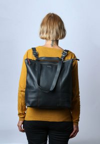 Zwarte leren tote bag met een gestructureerde vorm, rode accenten en verstelbare schouderbanden, met een rits bovenopening.