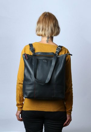 Sac cabas en cuir noir avec une forme structurée, des accents rouges et des bretelles réglables, doté d'une fermeture supérieure zippée.