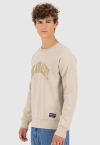 Beige sweatshirt met "Life A'RaliFe" in textuur gouden letters. Kenmerkt een ronde hals, geribbelde manchetten en een zij-label van het merk.