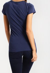 Mörkblå kortärmad skjorta i slätt tyg, med en figursydd design och en lätt rynkning i ryggen.