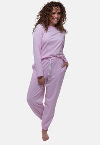 Rosa långärmad topp och matchande joggerbyxor, tillverkade av mjukt tyg, med elastisk midja med dragsko och sidofickor.