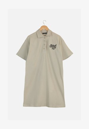 Robe polo beige à manches courtes avec col et trois boutons, ornée d'un texte brodé noir sur la poitrine gauche. Tissu lisse et léger.