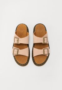 Sandales en suède rose avec deux boucles réglables, semelle intérieure en suède marron et semelle en caoutchouc noire avec des coutures jaunes.