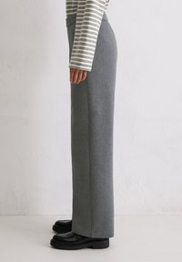 Szare, proste spodnie z miękkiego, elastycznego materiału, z wysokim stanem, zestawione z czarnymi butami na platformie.