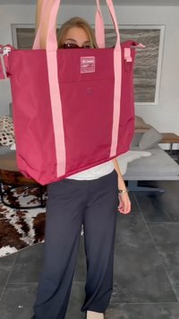 Velika burgundska torba na rame s roza trakami, izdelana iz trpežne tkanine, z sprednjim žepom in z zadrgo.