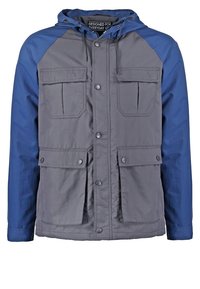 Grå og blå jakke med hætte, frontknapper, to brystlommer og to nedre lommer med klap mod hvid baggrund.