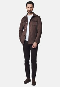 Brązowa zamszowa kurtka z kołnierzem, dwiema przednimi kieszeniami i zapięciem na guziki. Nosić na białej koszulce i w połączeniu z czarnymi spodniami oraz butami.