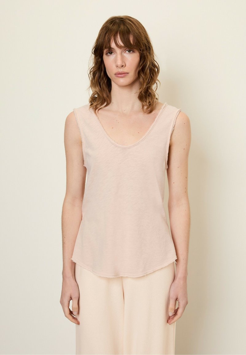 Jasnoróżowy top na ramiączkach z głębokim dekoltem w kształcie U, surowymi szwami i lekko rozszerzanym krojem. Wykonany z miękkiej, strukturalnej tkaniny.