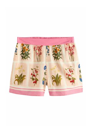 Hellrosa Shorts mit roten, blauen und grünen Blumenmustern und einem einfarbigen pinken Bund, getragen im Freien vor grünem Laub.