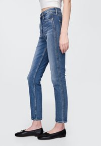 Mėlynos aukštu liemeniu džinsinės kelnės iš džinsinio audinio, tiesaus silueto su šoninėmis siūlėmis. Derinamos su juodais baleto bateliais. Lygus audinys, klasikinis dizainas.