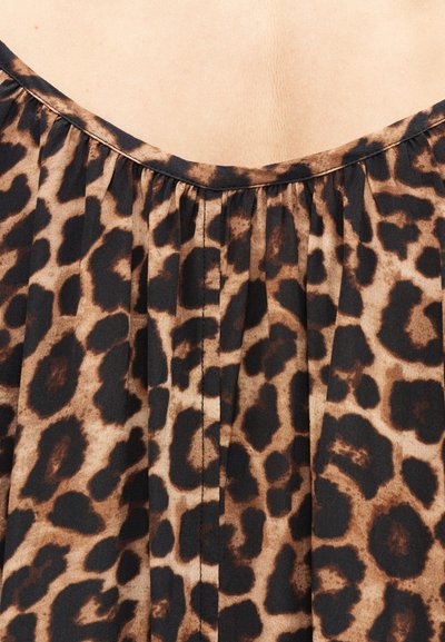 Υφασμα με σχέδιο λεοπάρ, πτυχώσεις και στρογγυλή λαιμόκοψη σε ανοιχτόχρωμο δέρμα φόντο.
