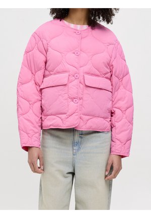 Personne portant une veste matelassée rose avec des boutons et des poches à rabat, associée à un jean bleu clair.