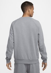 Szary sweatshirt z okrągłym dekoltem, ściągaczami na rękawach i dolnym brzegu. Posiada gładką powierzchnię, rękawy raglanowe i minimalne logo na dolnej części pleców.