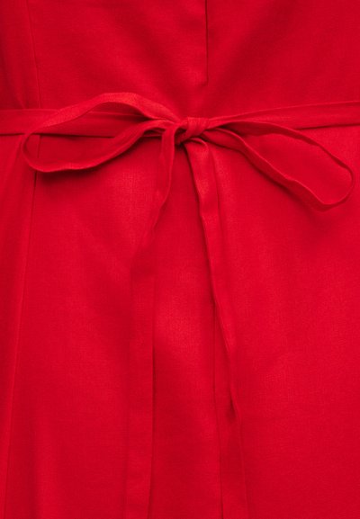 Heldere rode stof gebonden in een eenvoudige strik met lange lussen en uiteinden, met een gladde textuur en levendige kleur.