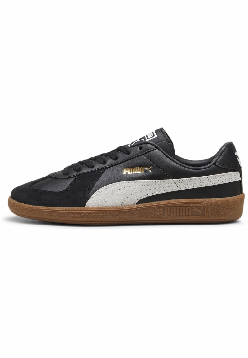 Schwarze und graue Turnschuhe mit einem Obermaterial aus Wildleder und Leder, Gummisohle und goldenen Akzenten sowie einem Logo an der Seite und auf der Zunge.