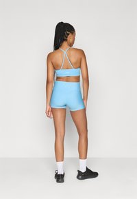 Ανοιχτό μπλε αθλητικό σουτιέν και αντίστοιχα ψηλόμεσα σορτσάκια, κατασκευασμένα από ελαστικό ύφασμα. Διαθέτουν ρυθμιζόμενους ιμάντες και λεπτομέρεια με το λογότυπο στο πίσω μέρος.